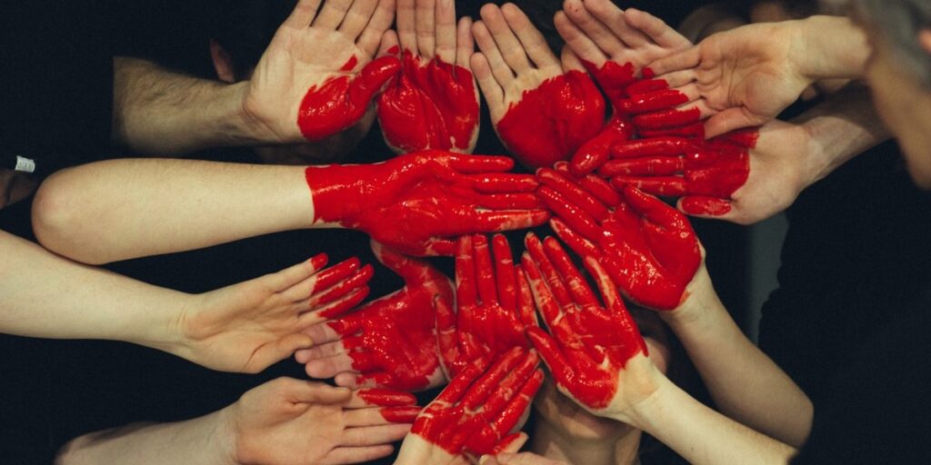 a group of hands forming together with a large painted heart