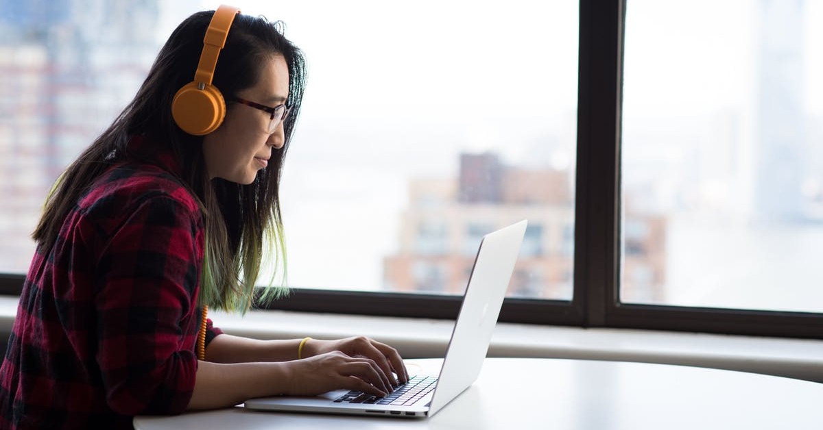 Woman at a laptop wearing headphones taking an online course.