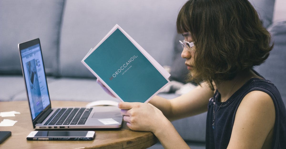 student at her computer reading a book