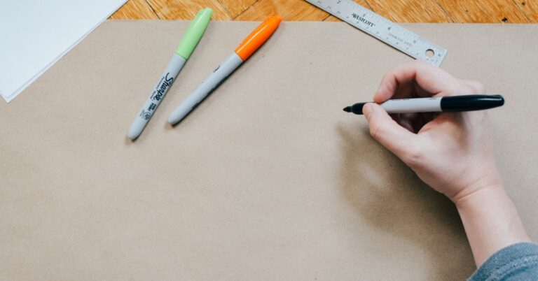 hand holding a sharpy beginning to draw on brown paper