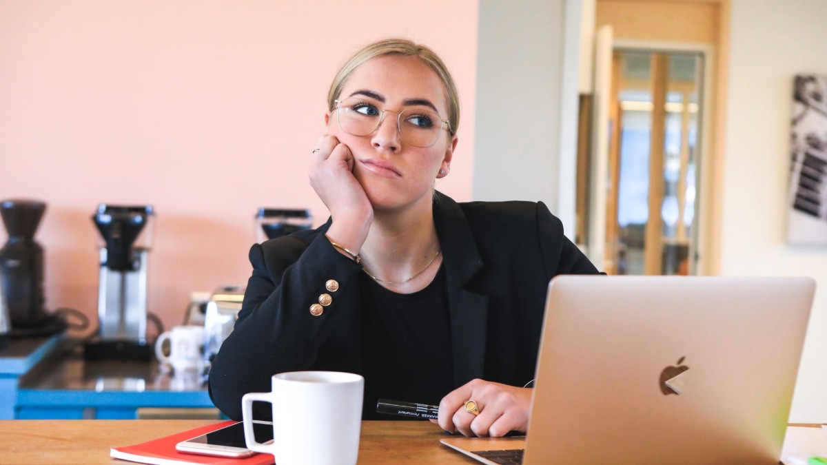 Woman procrastinating as she sits in front of a computer.