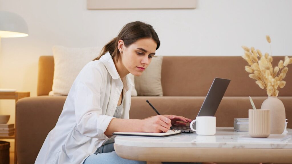 Woman sitting at a coffee table in front of a computer learning for an online course.