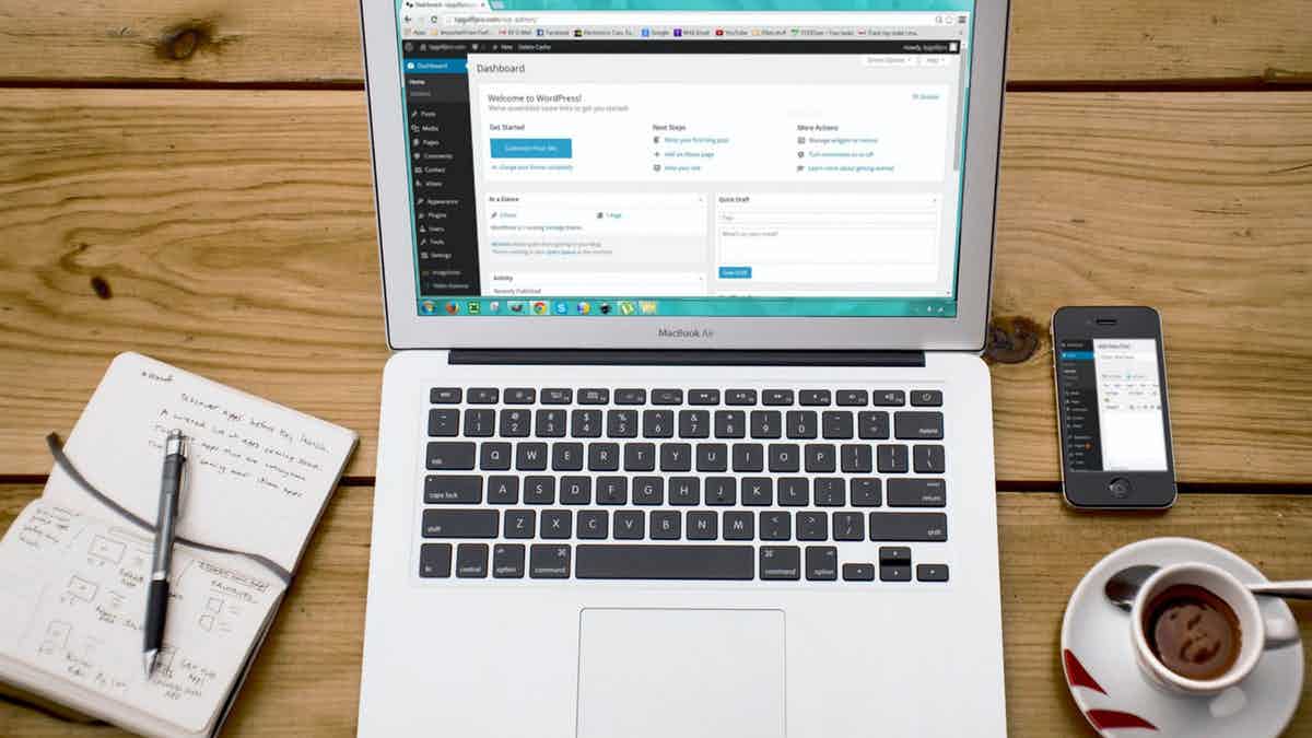 Laptop on desk with coffee showing image of a WordPress website