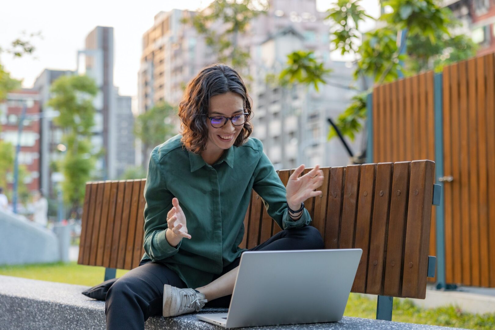 person sitting on an outdoor bench in front of a laptop