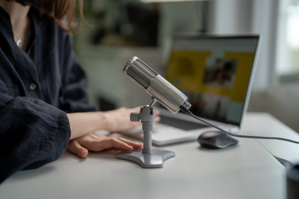 person using laptop and microphone on desk