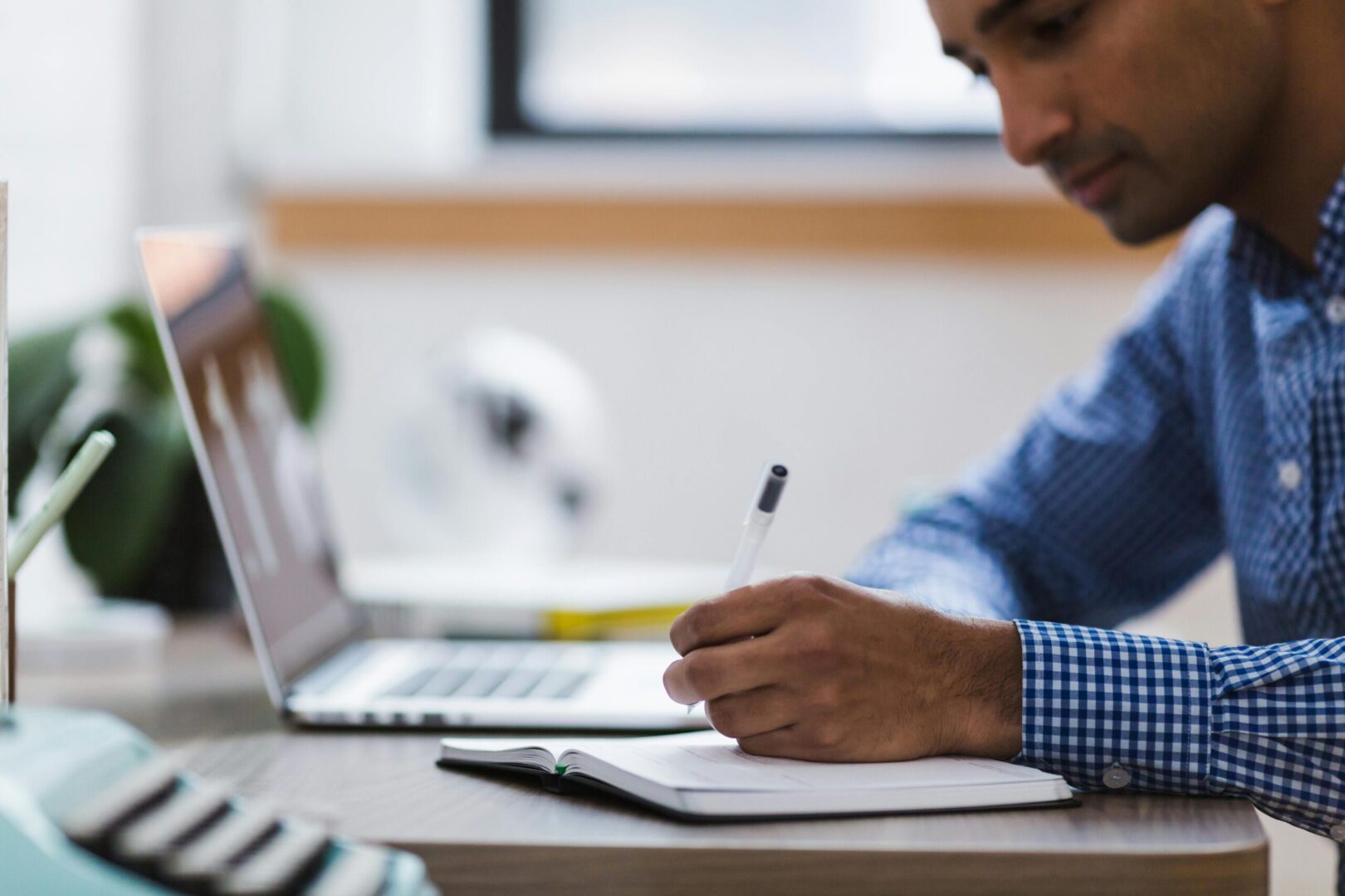 man writing with pen and paper on desk